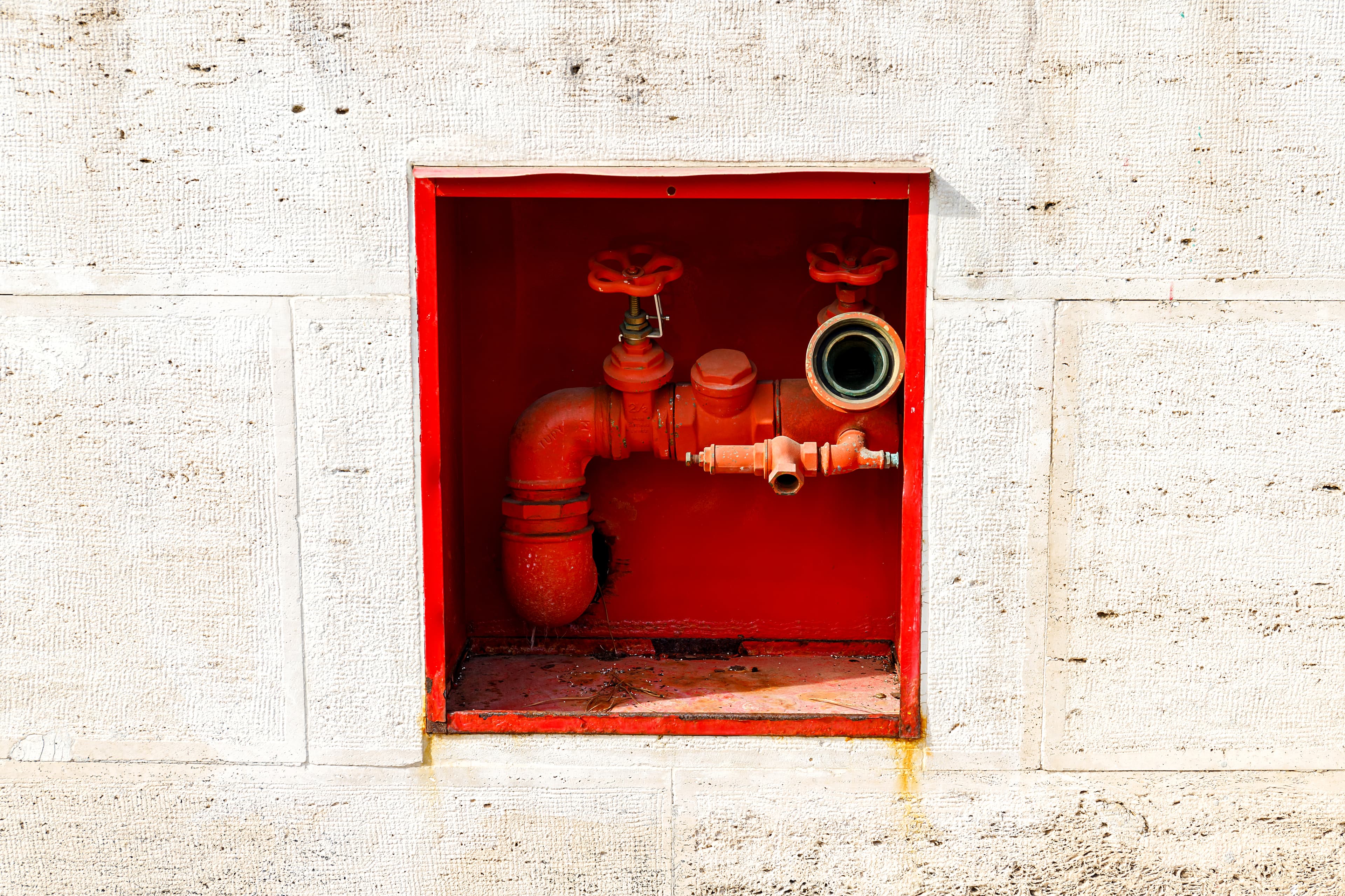 Red fire hydrant connection box set into an exterior wall